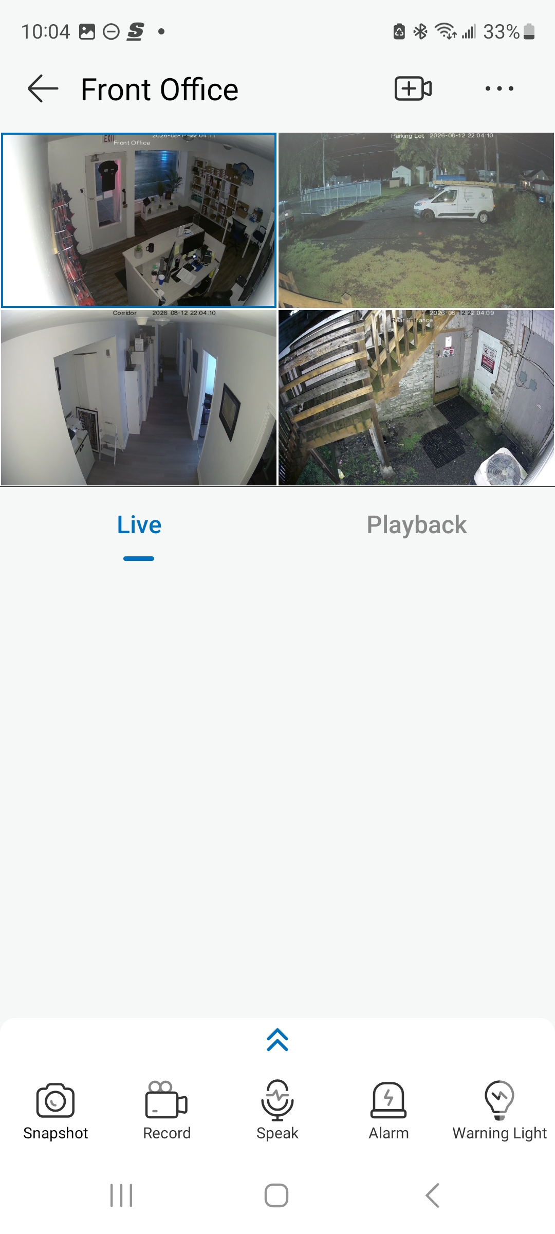 AiBase mobile app showing a live quad-camera view — front office, parking lot, corridor, and rear entrance — on a smartphone